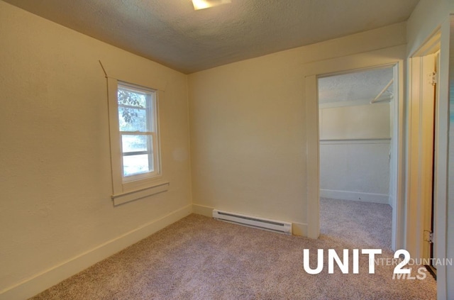 carpeted spare room with a textured ceiling, baseboards, and a baseboard radiator