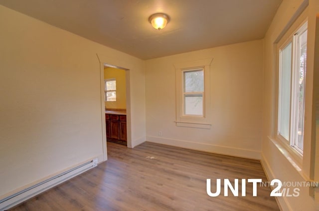 spare room featuring wood finished floors, baseboards, and a baseboard radiator