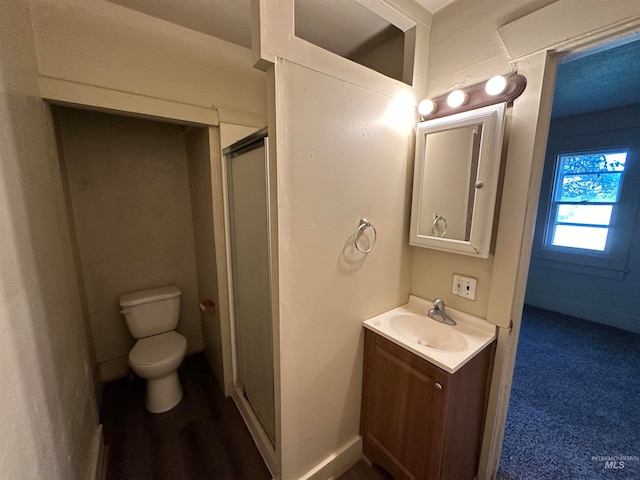 bathroom with vanity, a shower stall, toilet, and baseboards