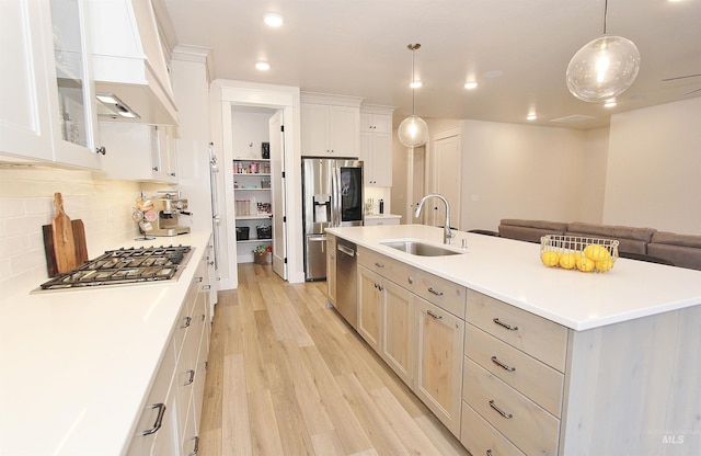 520 S Prospector Ln, Eagle, ID 83616 - kitchen with a sink, appliances with stainless steel finishes, premium range hood, light wood finished floors, and a kitchen island with sink