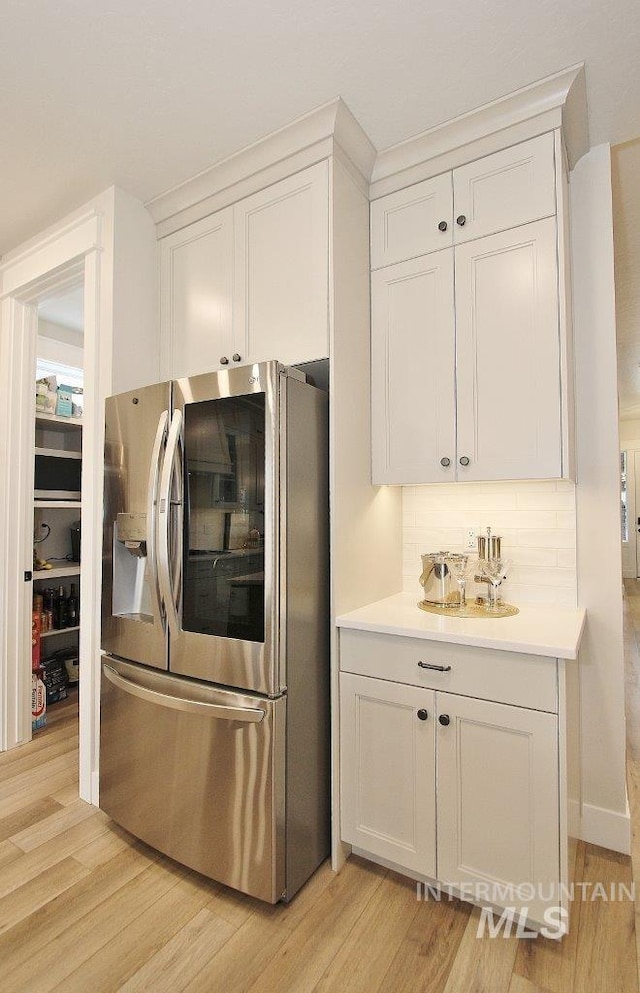520 S Prospector Ln, Eagle, ID 83616 - kitchen with stainless steel refrigerator with ice dispenser, light wood-style floors, light countertops, white cabinets, and decorative backsplash