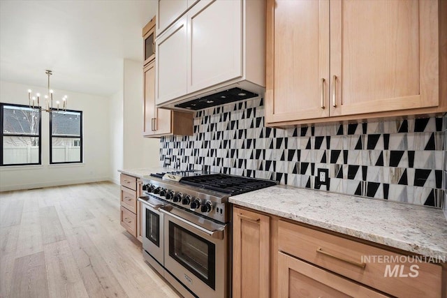 kitchen with a notable chandelier, light hardwood / wood-style floors, double oven range, light brown cabinetry, and light stone counters