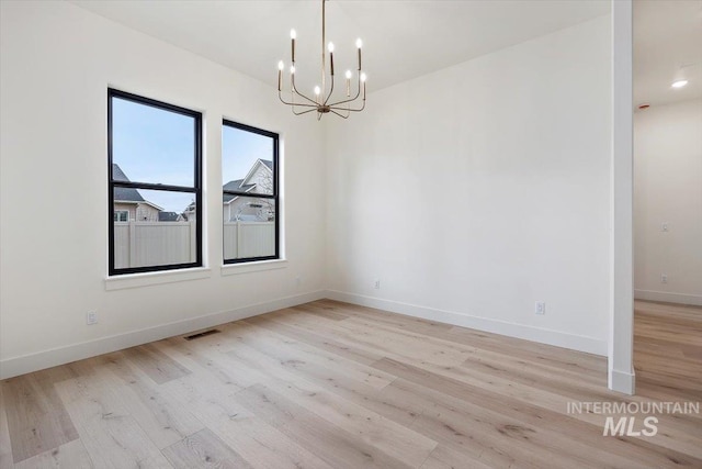 unfurnished dining area featuring light wood-type flooring and a notable chandelier