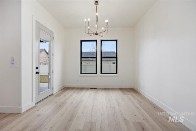 unfurnished dining area featuring light wood-type flooring and an inviting chandelier