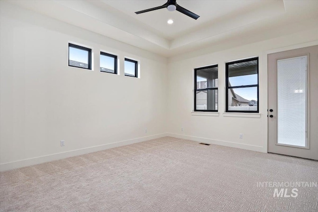 carpeted spare room with ceiling fan and a tray ceiling