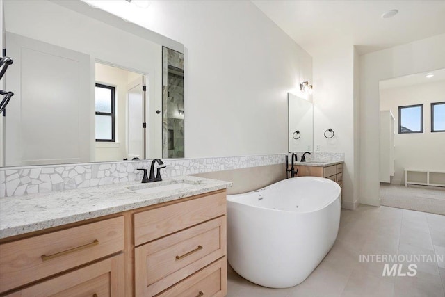 bathroom with vanity, a bath, and tile patterned flooring