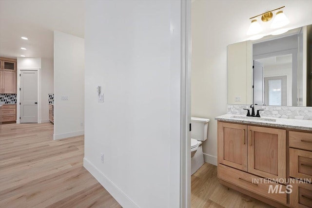 bathroom featuring decorative backsplash, wood-type flooring, toilet, and vanity