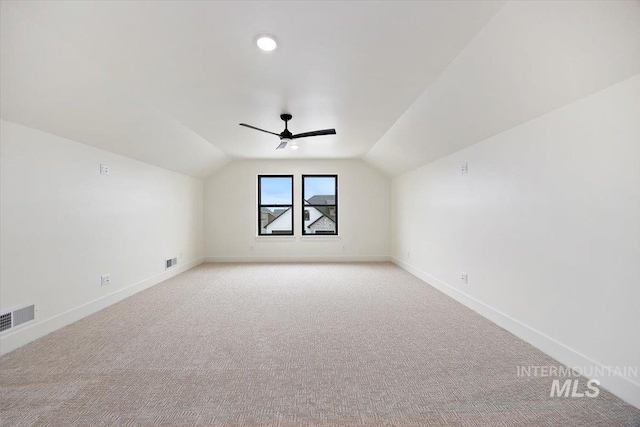 additional living space featuring ceiling fan, light colored carpet, and vaulted ceiling