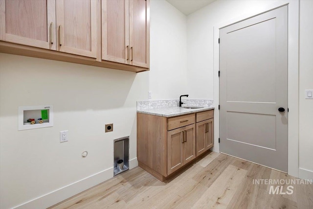 clothes washing area featuring sink, light hardwood / wood-style flooring, washer hookup, hookup for an electric dryer, and cabinets