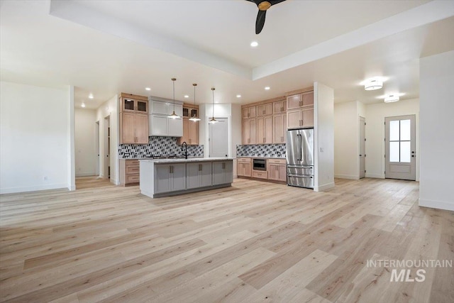 kitchen featuring a center island with sink, appliances with stainless steel finishes, tasteful backsplash, hanging light fixtures, and sink