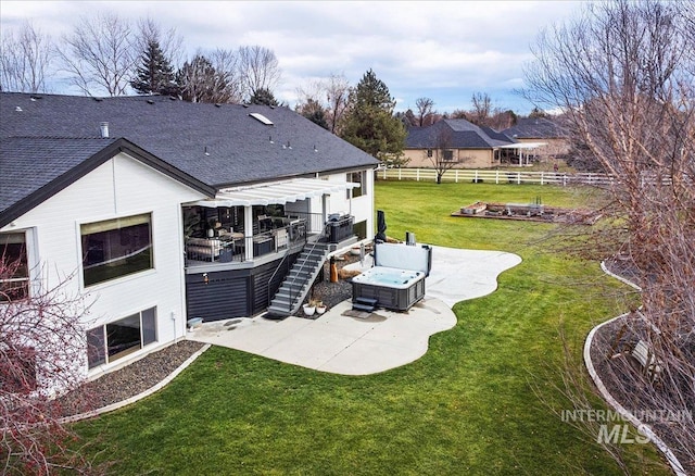 back of house featuring a patio, a fire pit, a lawn, a wooden deck, and a hot tub