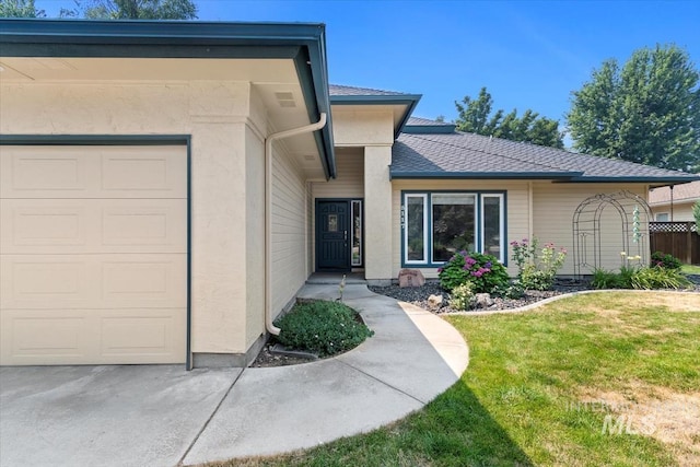 view of exterior entry with a garage and a lawn