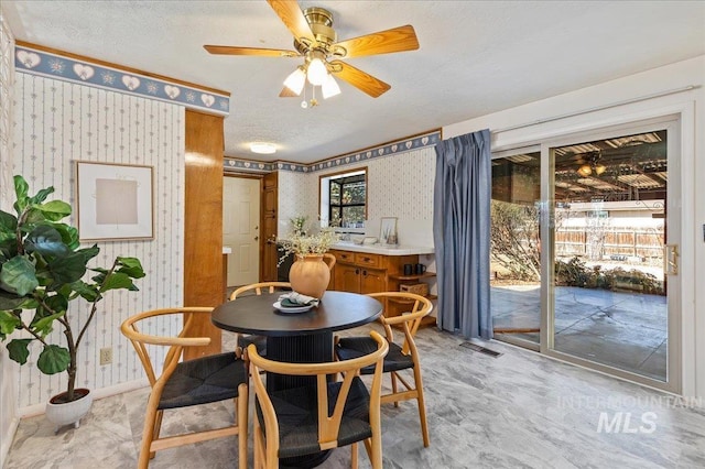 dining area with baseboards, visible vents, wallpapered walls, ceiling fan, and a textured ceiling