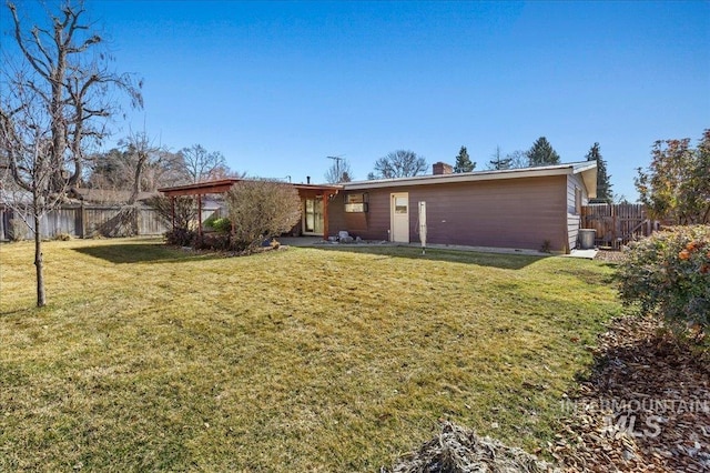 back of property with a lawn, a fenced backyard, and a chimney