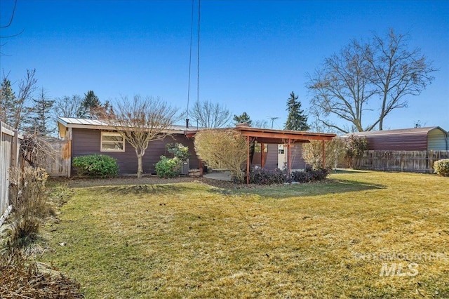 rear view of house with a standing seam roof, a yard, a fenced backyard, and metal roof