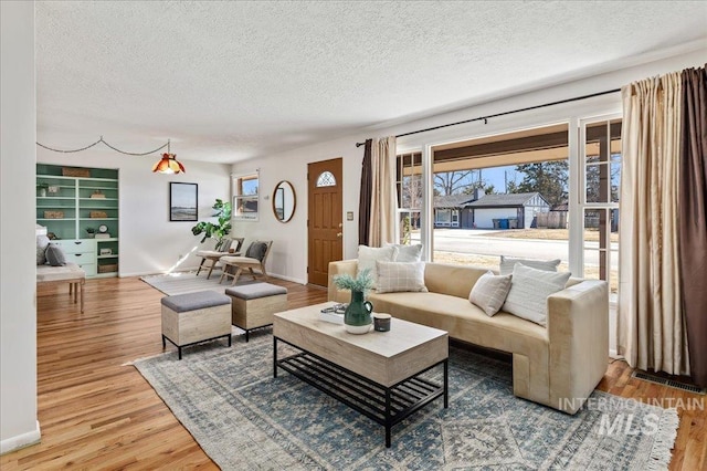 living room featuring wood finished floors, baseboards, and a textured ceiling