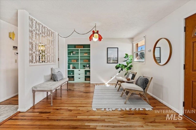 sitting room featuring a textured ceiling, baseboards, and wood finished floors