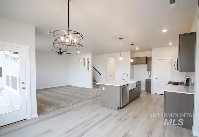 kitchen with pendant lighting, light countertops, a sink, stainless steel appliances, and light wood finished floors