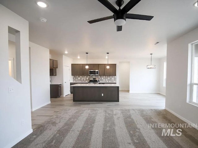 kitchen featuring dark brown cabinetry, light countertops, backsplash, ceiling fan, and appliances with stainless steel finishes