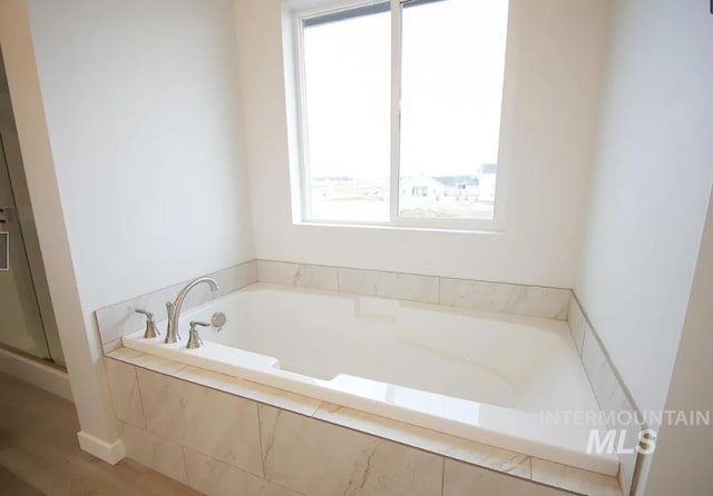 full bathroom featuring a stall shower, a garden tub, and wood finished floors
