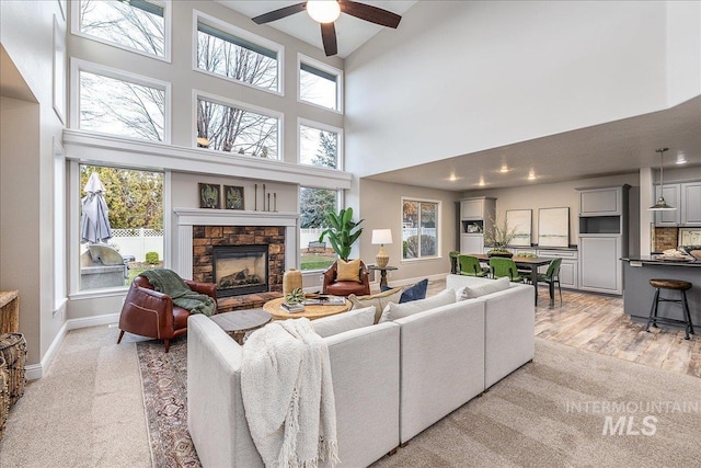 living room with ceiling fan, a fireplace, and a high ceiling