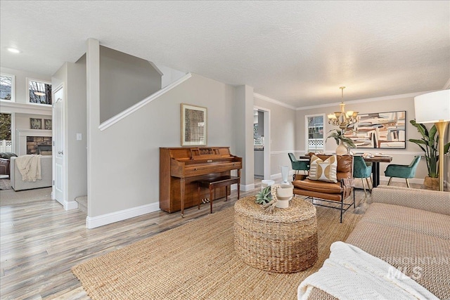 living room featuring a fireplace, a textured ceiling, light hardwood / wood-style flooring, and a notable chandelier