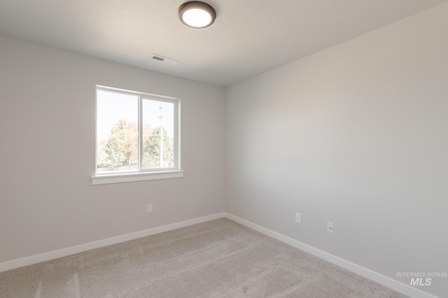 empty room with carpet floors, baseboards, and visible vents