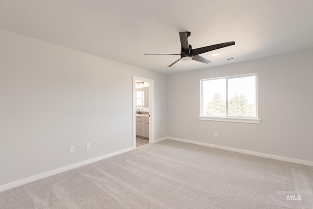 unfurnished bedroom featuring light carpet, ensuite bathroom, visible vents, and baseboards