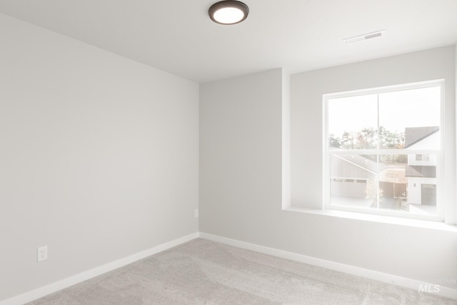 carpeted empty room featuring visible vents and baseboards