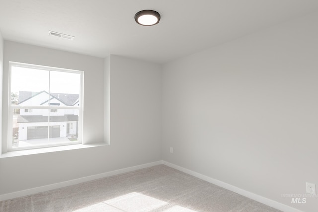 unfurnished room featuring carpet floors, visible vents, and baseboards