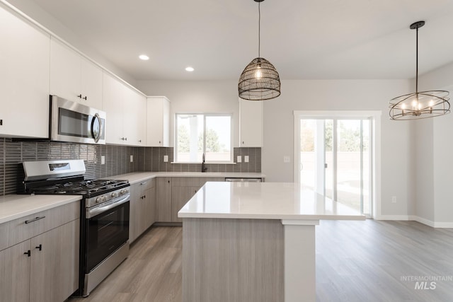 kitchen with appliances with stainless steel finishes, light countertops, light wood-style floors, and backsplash