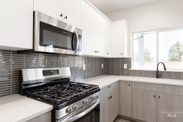 kitchen featuring appliances with stainless steel finishes, backsplash, and a sink