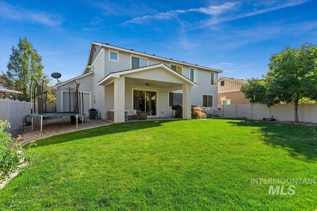 rear view of property with central AC unit, a trampoline, and a lawn