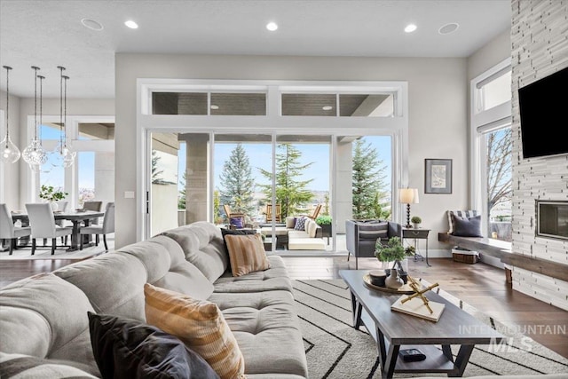 living area with recessed lighting, a fireplace, and wood finished floors