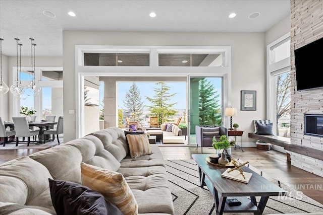 living area with recessed lighting, a fireplace, baseboards, and wood finished floors