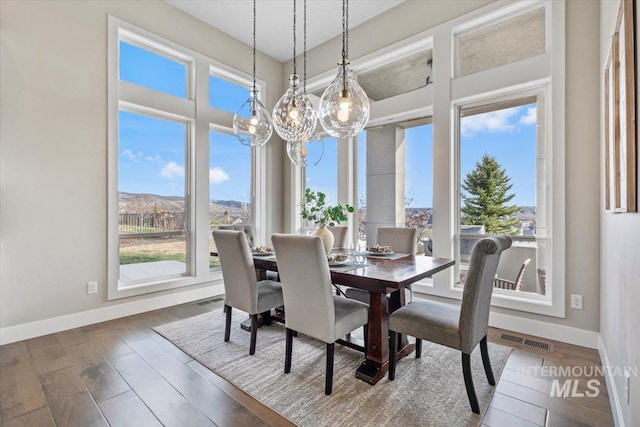 dining space with a notable chandelier, wood finished floors, visible vents, and baseboards