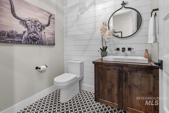 half bathroom with baseboards, toilet, and vanity