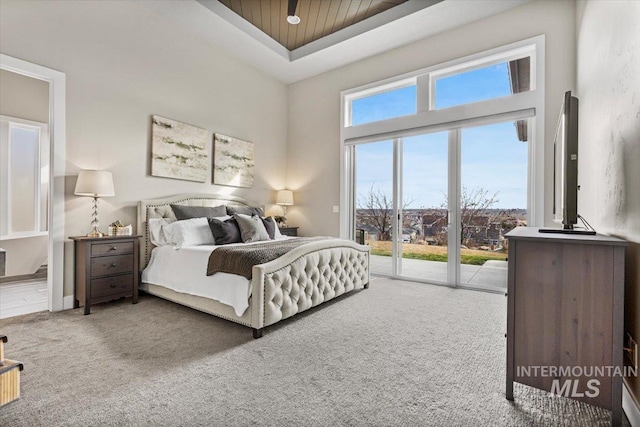 bedroom with access to exterior, a raised ceiling, and carpet