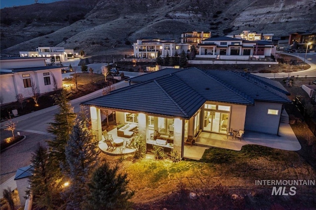 back of house with a tiled roof, a patio area, a mountain view, and stucco siding