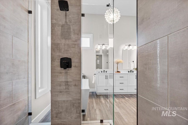 bathroom with baseboards, tiled shower, wood finished floors, and vanity