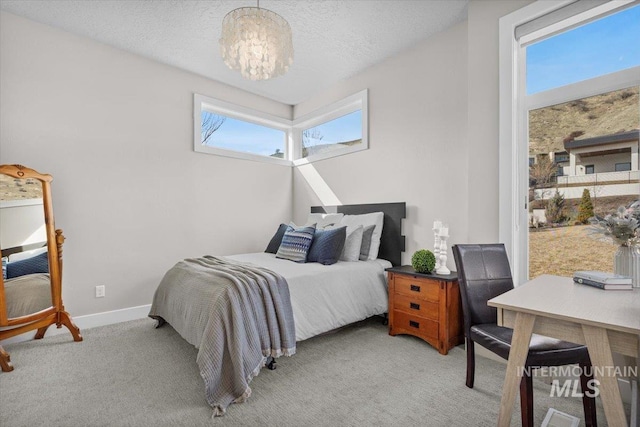 bedroom with a chandelier, light colored carpet, a textured ceiling, and baseboards