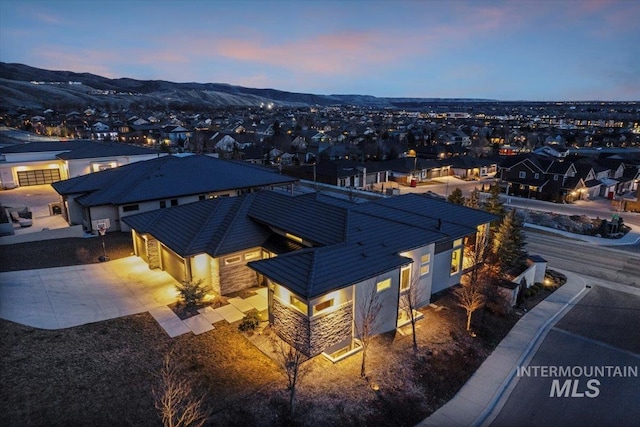 aerial view at dusk featuring a mountain view and a residential view