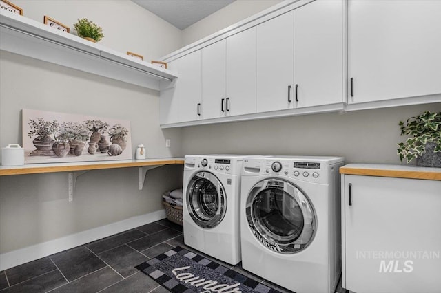 laundry room featuring cabinet space, washer and dryer, baseboards, and dark tile patterned flooring