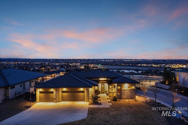 prairie-style home with a tiled roof, an attached garage, and driveway