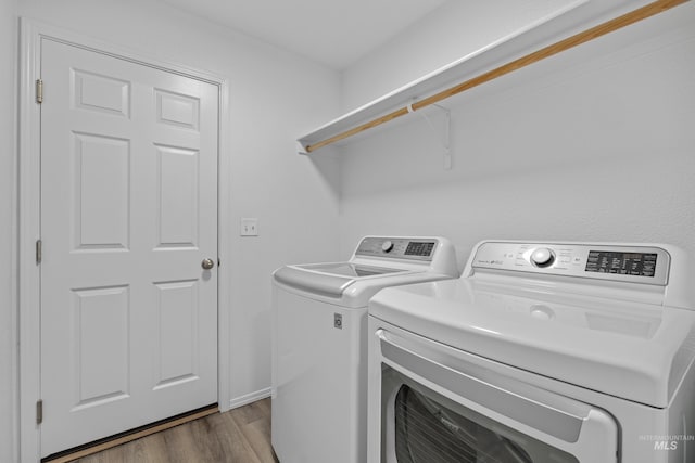 washroom with wood finished floors, laundry area, baseboards, and separate washer and dryer