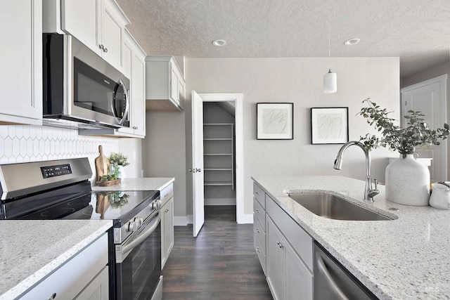 kitchen with white cabinetry, stainless steel appliances, light stone countertops, and sink