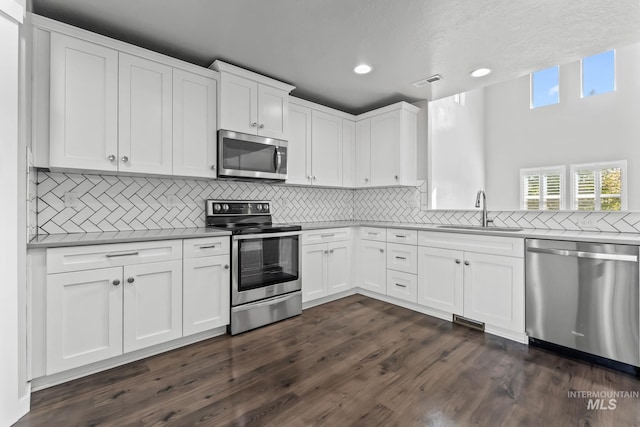 kitchen featuring decorative backsplash, visible vents, a sink, white cabinets, and stainless steel appliances