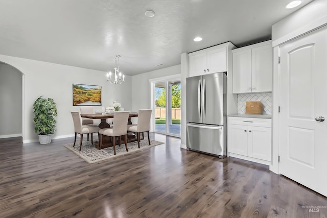 interior space featuring freestanding refrigerator, dark wood-style floors, white cabinets, arched walkways, and backsplash