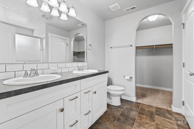 full bathroom with a sink, a walk in closet, a stall shower, and visible vents
