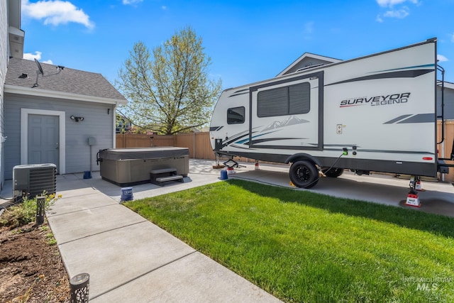 view of yard with a hot tub, central AC, and fence